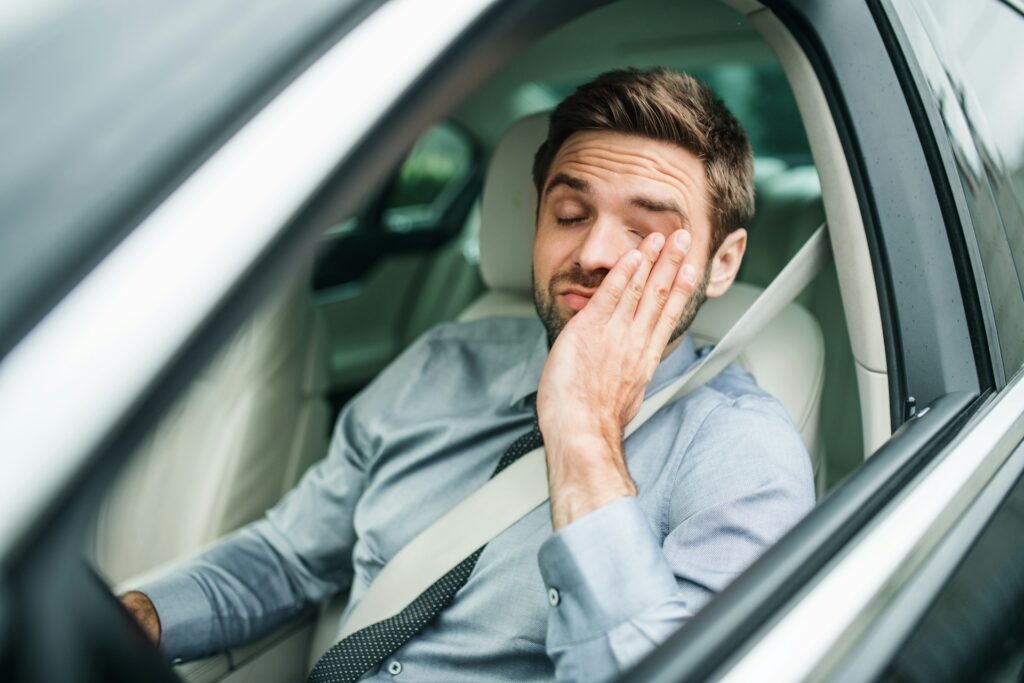 man with low energy driving a car