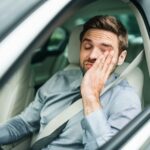 man with low energy driving a car